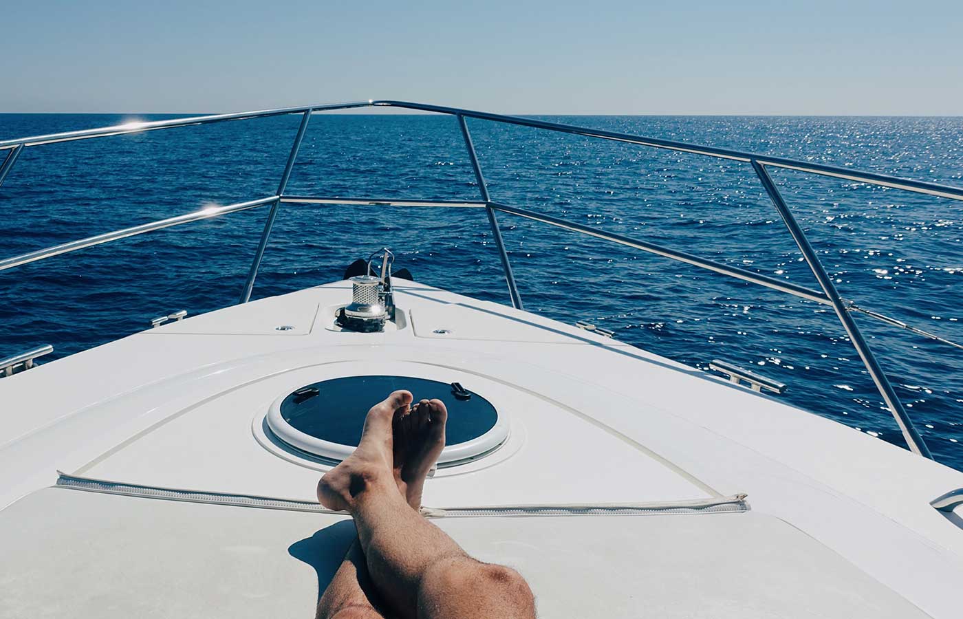 Legs crossed on a luxury boat, looking out into the water on a beautiful clear day.