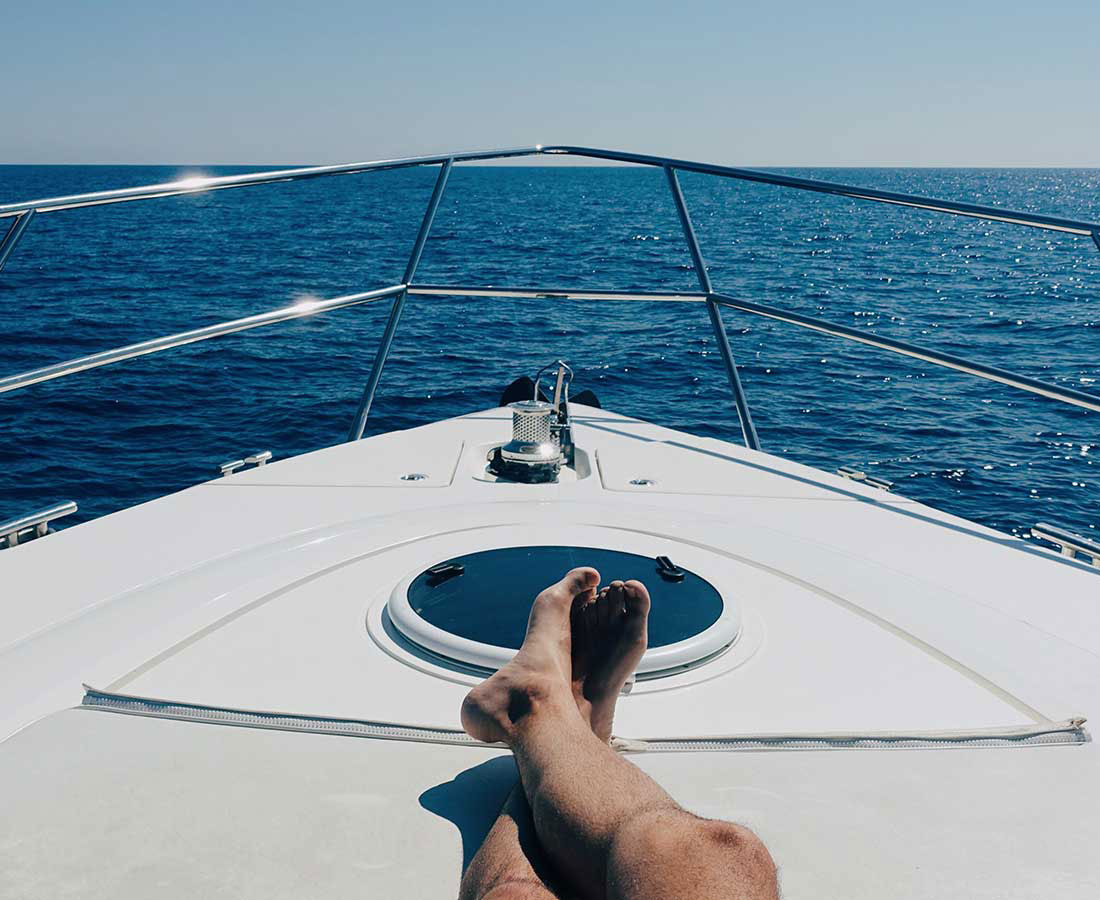 Legs crossed on a luxury boat, looking out into the water on a beautiful clear day.